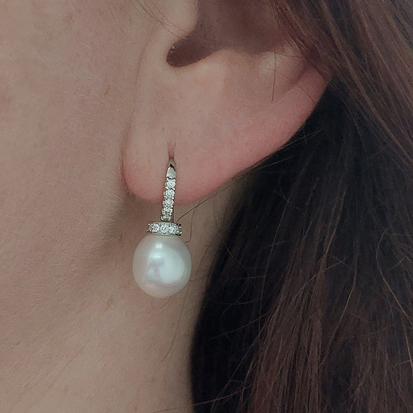 A pearl and diamond drop earring in white gold, modelled in an ear