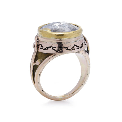 A large solitaire rose cut diamond ring in yellow and rose gold with decorative gallery and shank, on a white background