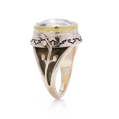 A large solitaire rose cut diamond ring in yellow and rose gold with decorative gallery and shank, on a white background