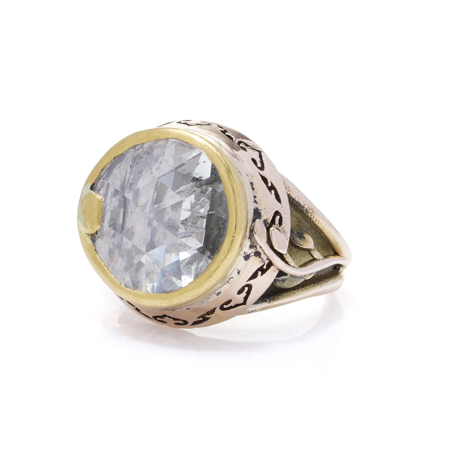 A large solitaire rose cut diamond ring in yellow and rose gold with decorative gallery and shank, on a white background