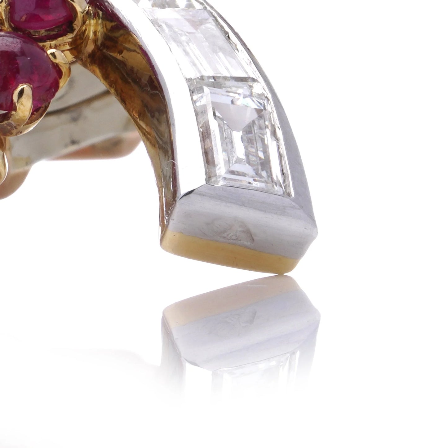 A gold and platinum leaf shaped brooch with baguette cut diamonds and cabochon cut rubies, on a white background