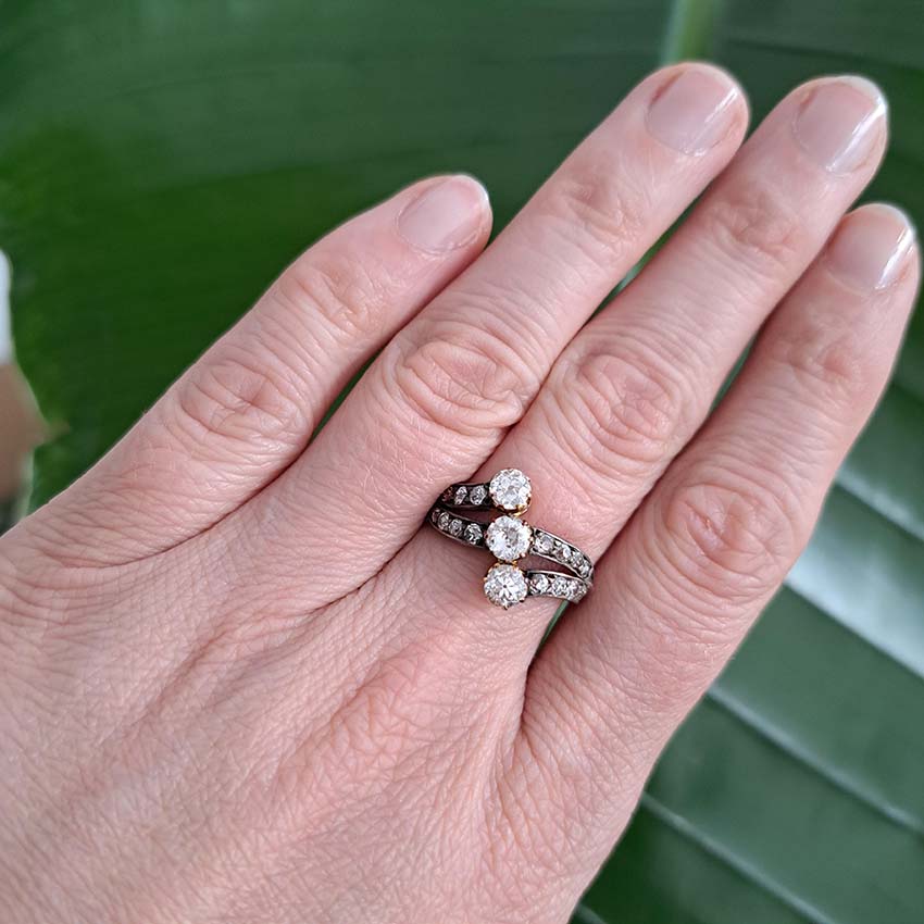 Victorian Antique Diamond Three Stone Banded Ring, diamond trilogy vertically set in asymmetrical design flanked by diamond banded shoulders in silver upon 18ct yellow gold