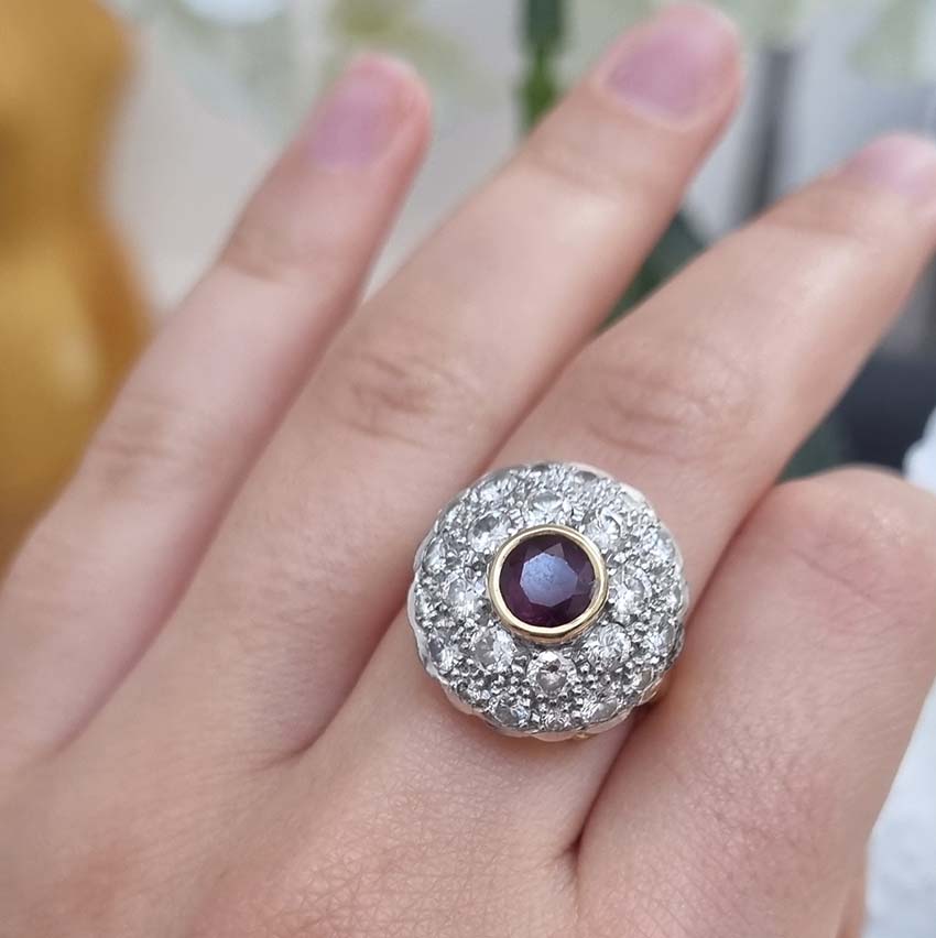 Ruby and Diamond Bombe Cluster Ring, central red ruby sits atop a domed bombe cluster of sparkling diamonds in white gold to an 18ct yellow gold shank with decorative scrolled shoulders