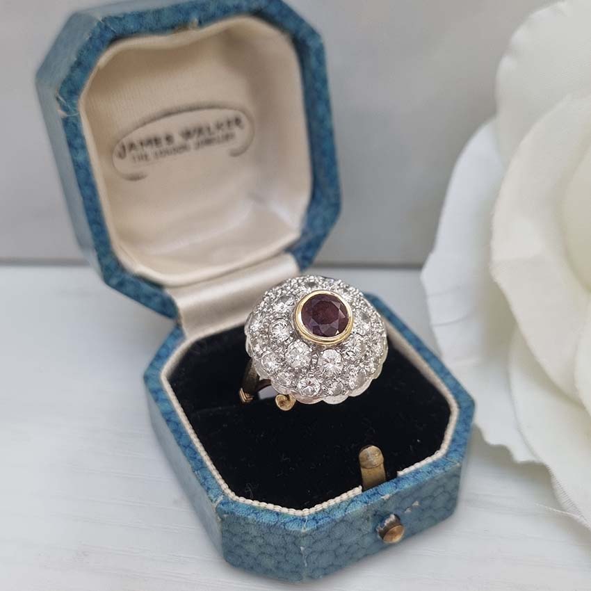 Ruby and Diamond Bombe Cluster Ring, central red ruby sits atop a domed bombe cluster of sparkling diamonds in white gold to an 18ct yellow gold shank with decorative scrolled shoulders