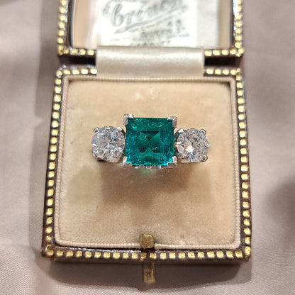 2.44 Square Step Cut Emerald and 1.50ct Diamond Three Stone Trilogy Engagement Ring in 18ct White Gold