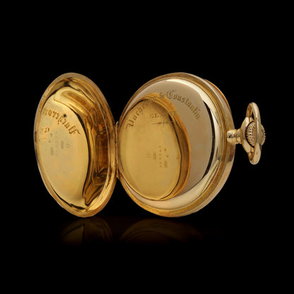 A yellow gold pocket watch with the back case open, engraved Vacheron & Constantin, on a black background