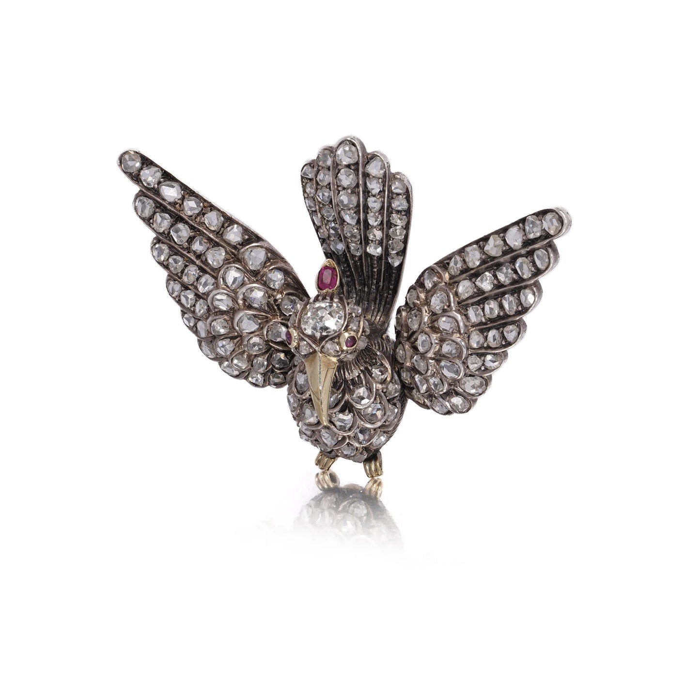 An antique bird in flight brooch set with diamonds and rubies, in silver and gold, on a white background