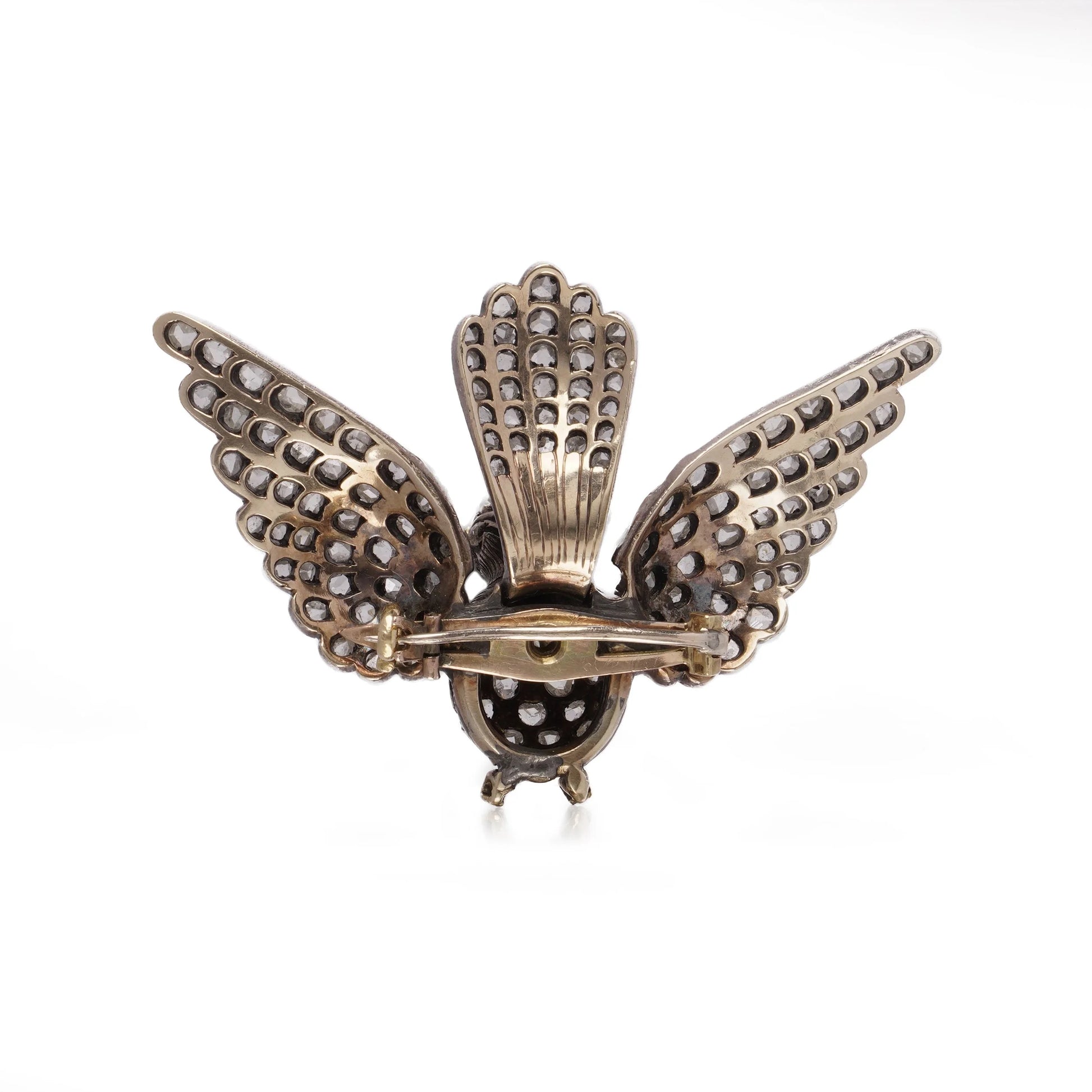 An antique bird in flight brooch set with diamonds and rubies, in silver and gold, on a white background