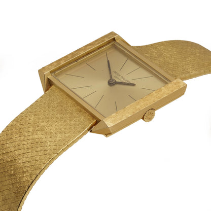 A yellow gold Patek Phillipe wristwatch with integrated bracelet, on a white background