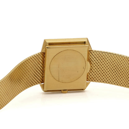 Close-up of a yellow gold watch case back with integrated bracelet, on a white background