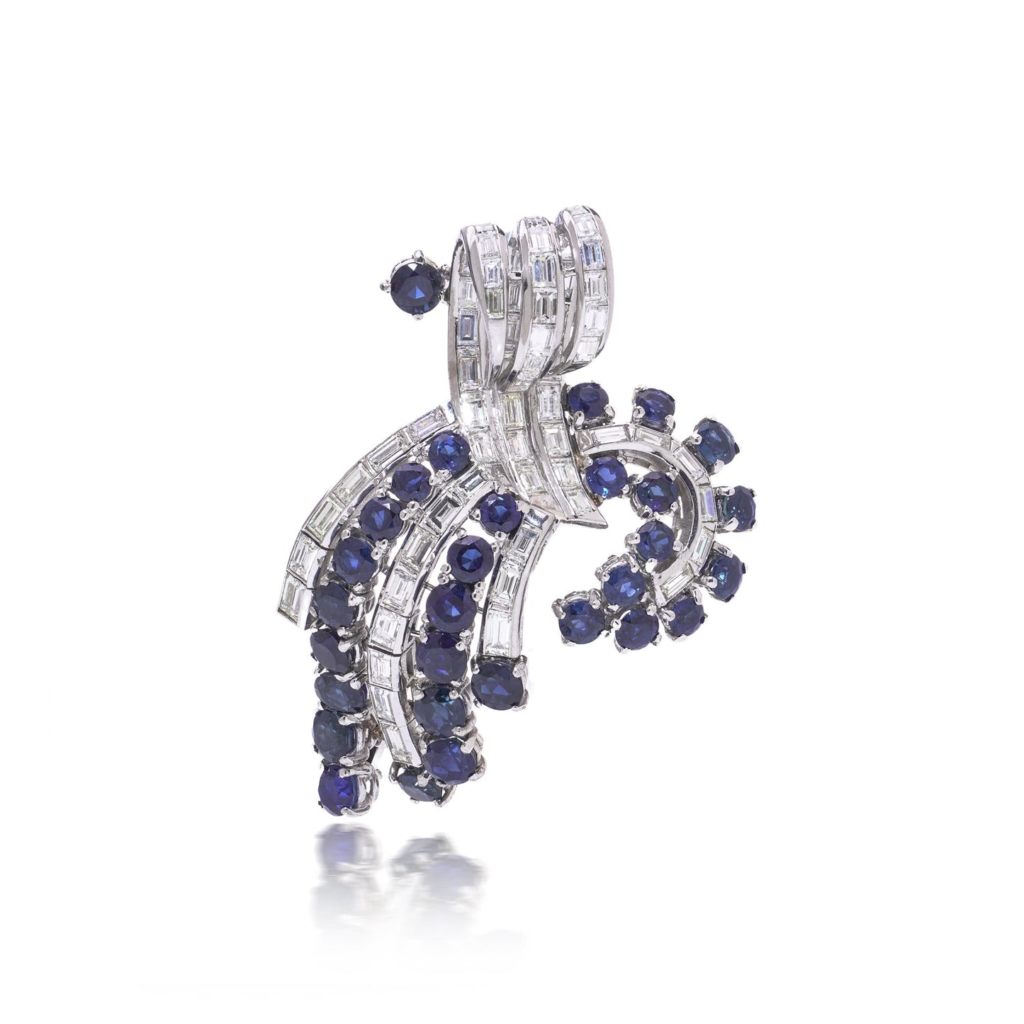 A decorative baguette cut diamond and round sapphire brooch in white metal, on a white background