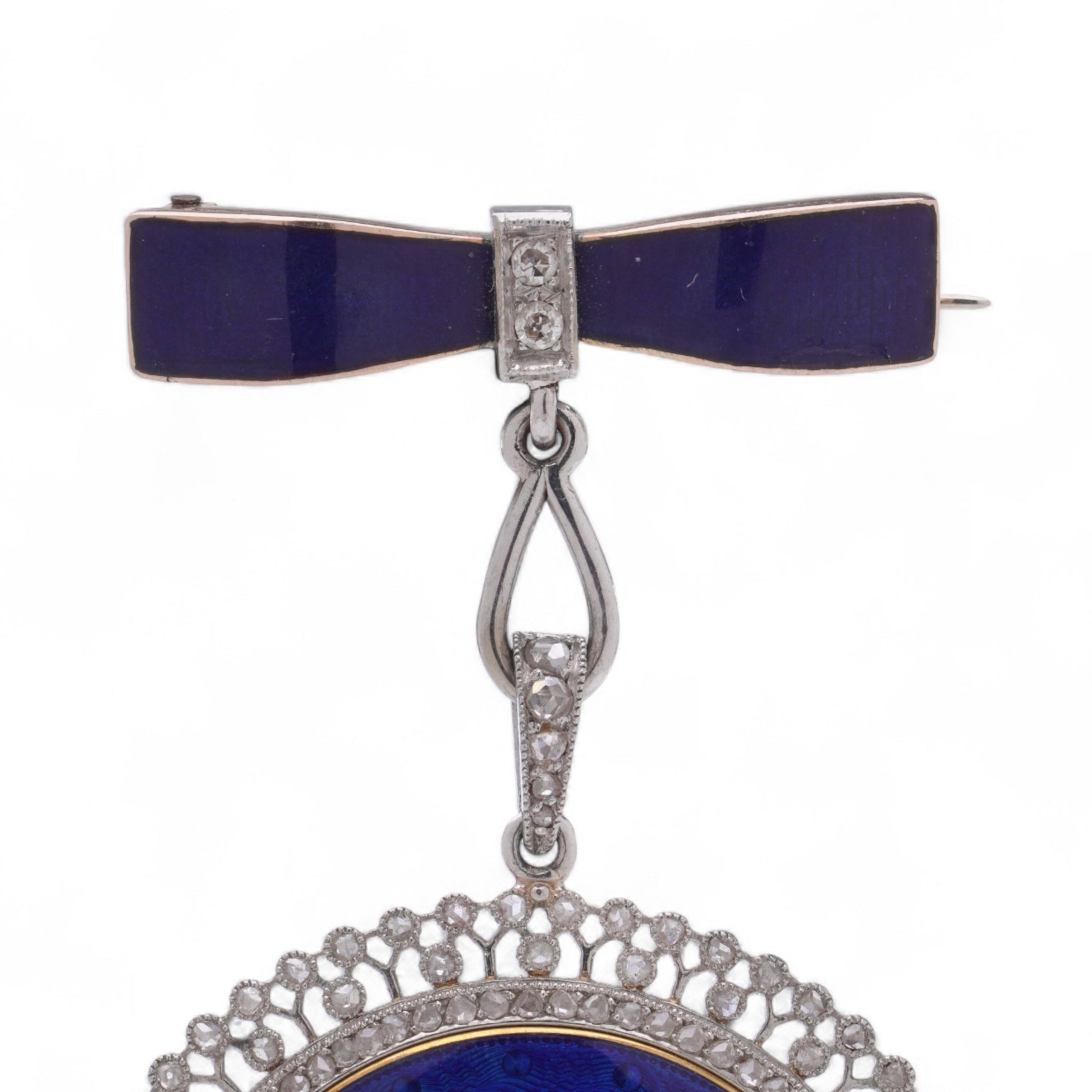 A blue enamel pendant pocket watch in silver with diamonds, suspended by a bow brooch fitting, on a white background