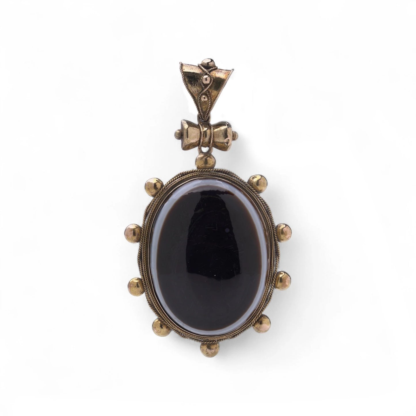 An oval pendant with a cabochon cut banded black agate with yellow gold hobnail bead border, on a white background