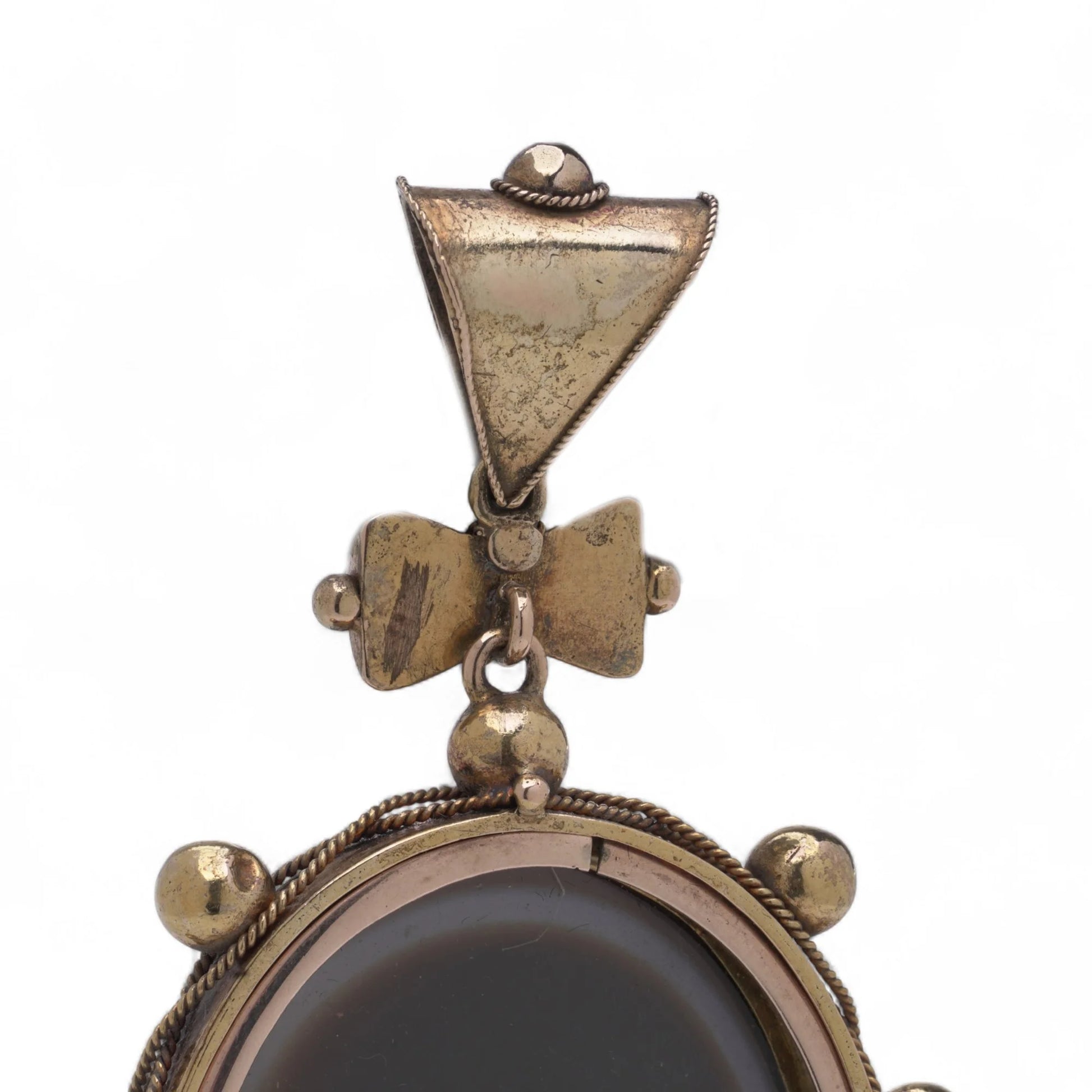 An oval pendant with a cabochon cut banded black agate with yellow gold hobnail bead border, on a white background