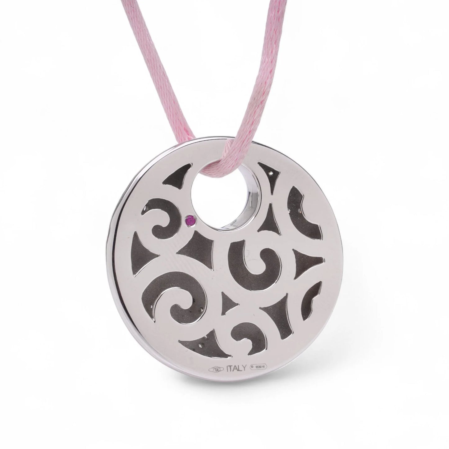 A circular white gold pendant with a pink sapphire on a pink cord, on a white background