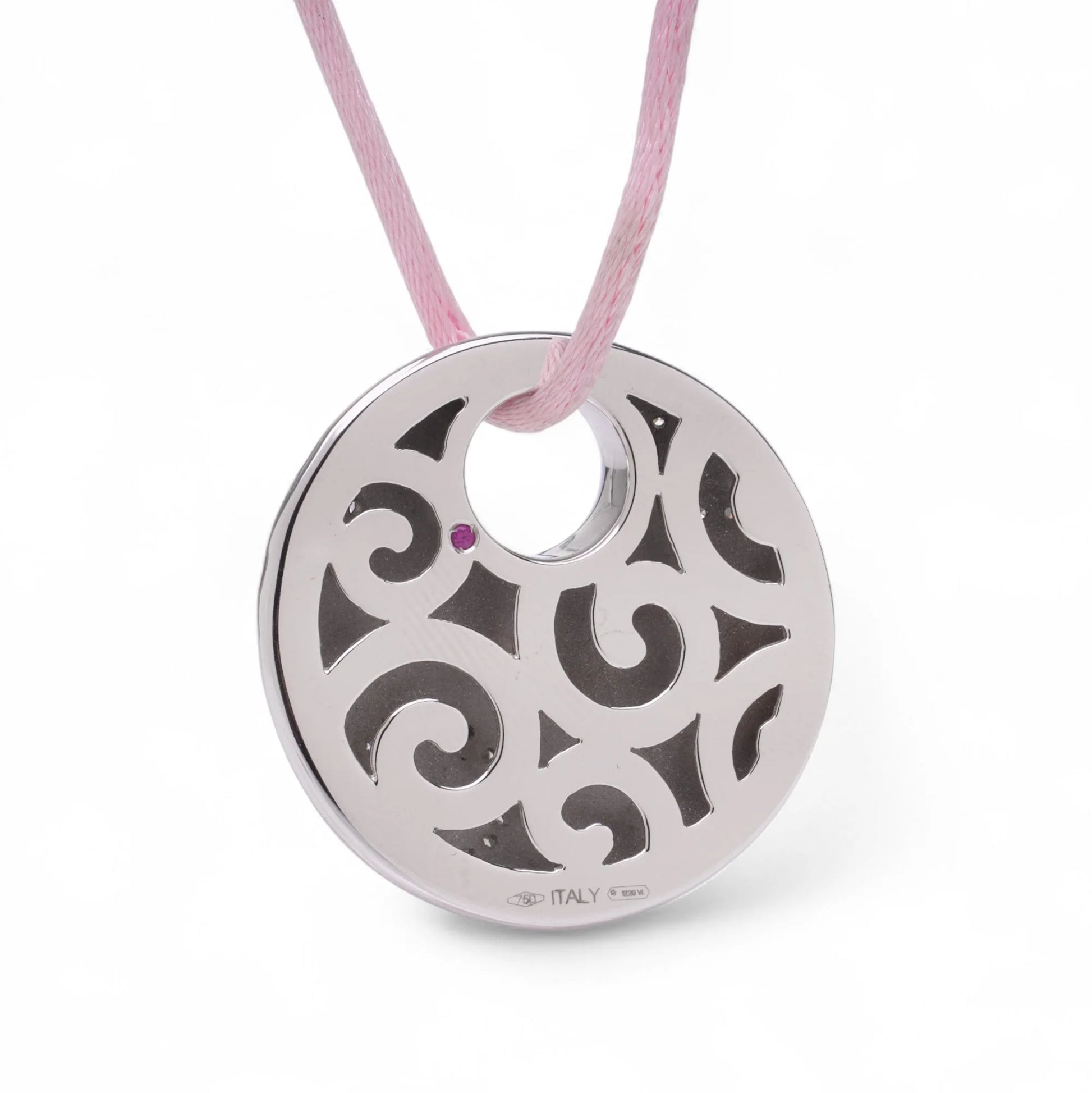 A circular white gold pendant with a pink sapphire on a pink cord, on a white background