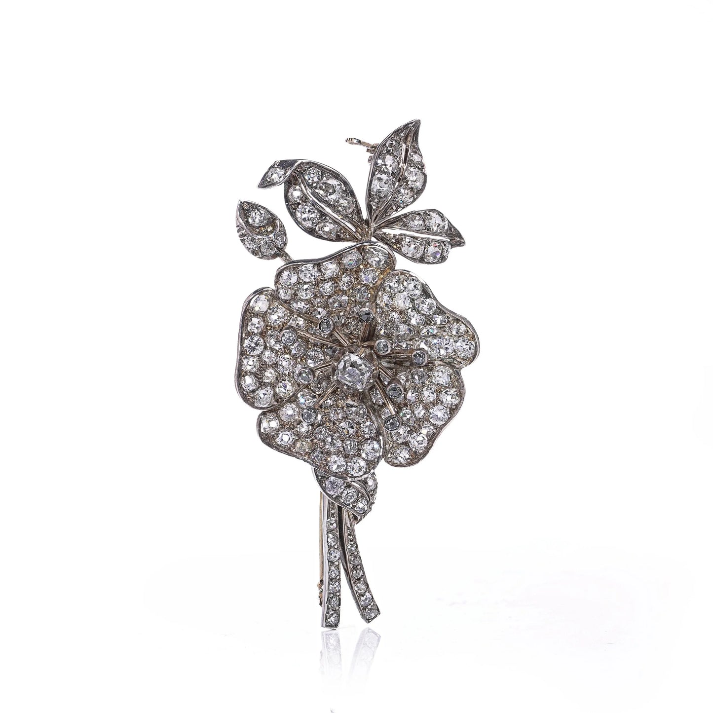 A decorative flower brooch set with diamonds, in silver and gold, on a white background