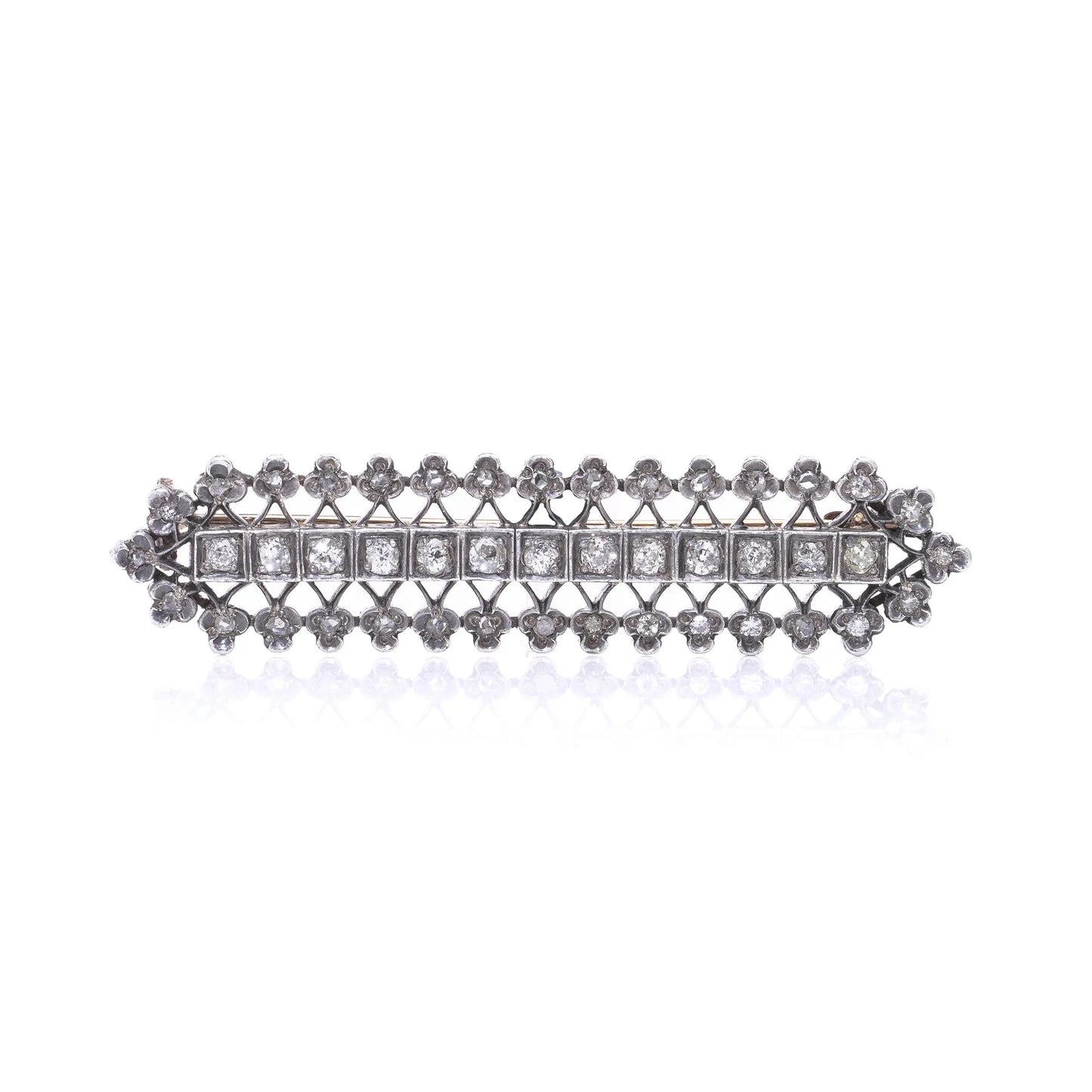 An openwork diamond set bar brooch in gold and silver, on a white background