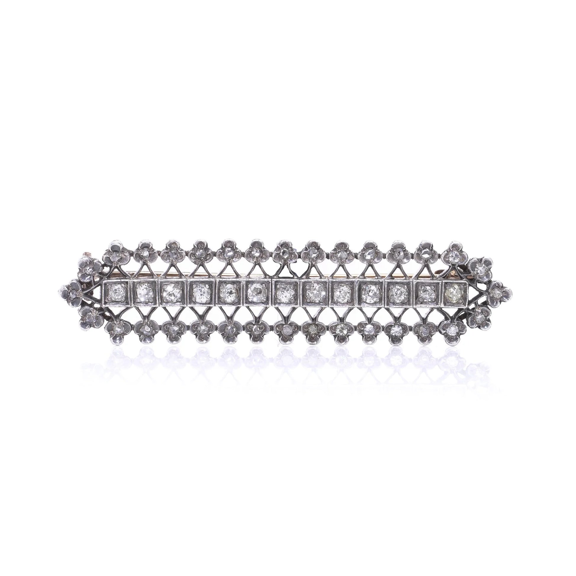An openwork diamond set bar brooch in gold and silver, on a white background