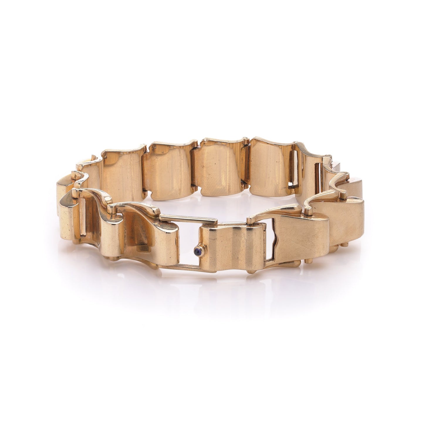 A yellow gold link bracelet with a sapphire set to the clasp, on a white background