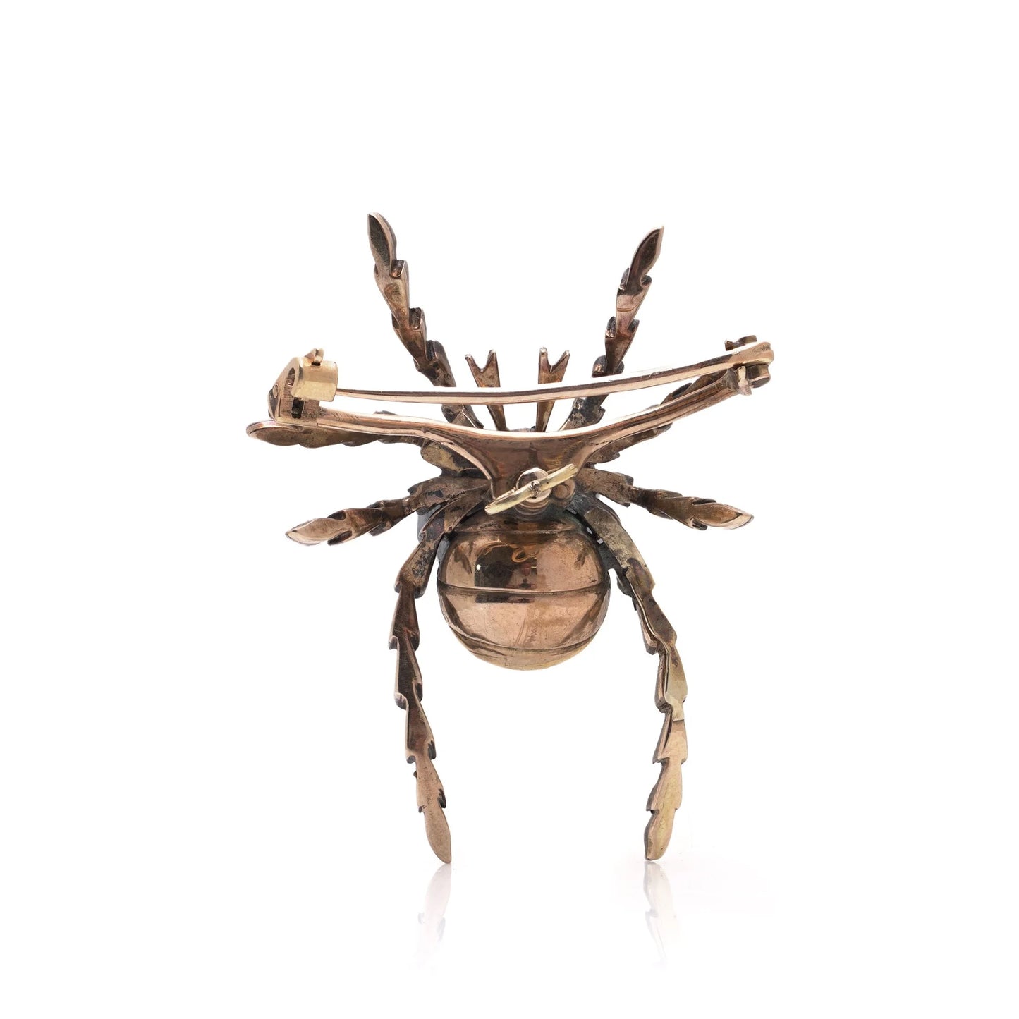 A spider brooch, in silver and gold, on a white background