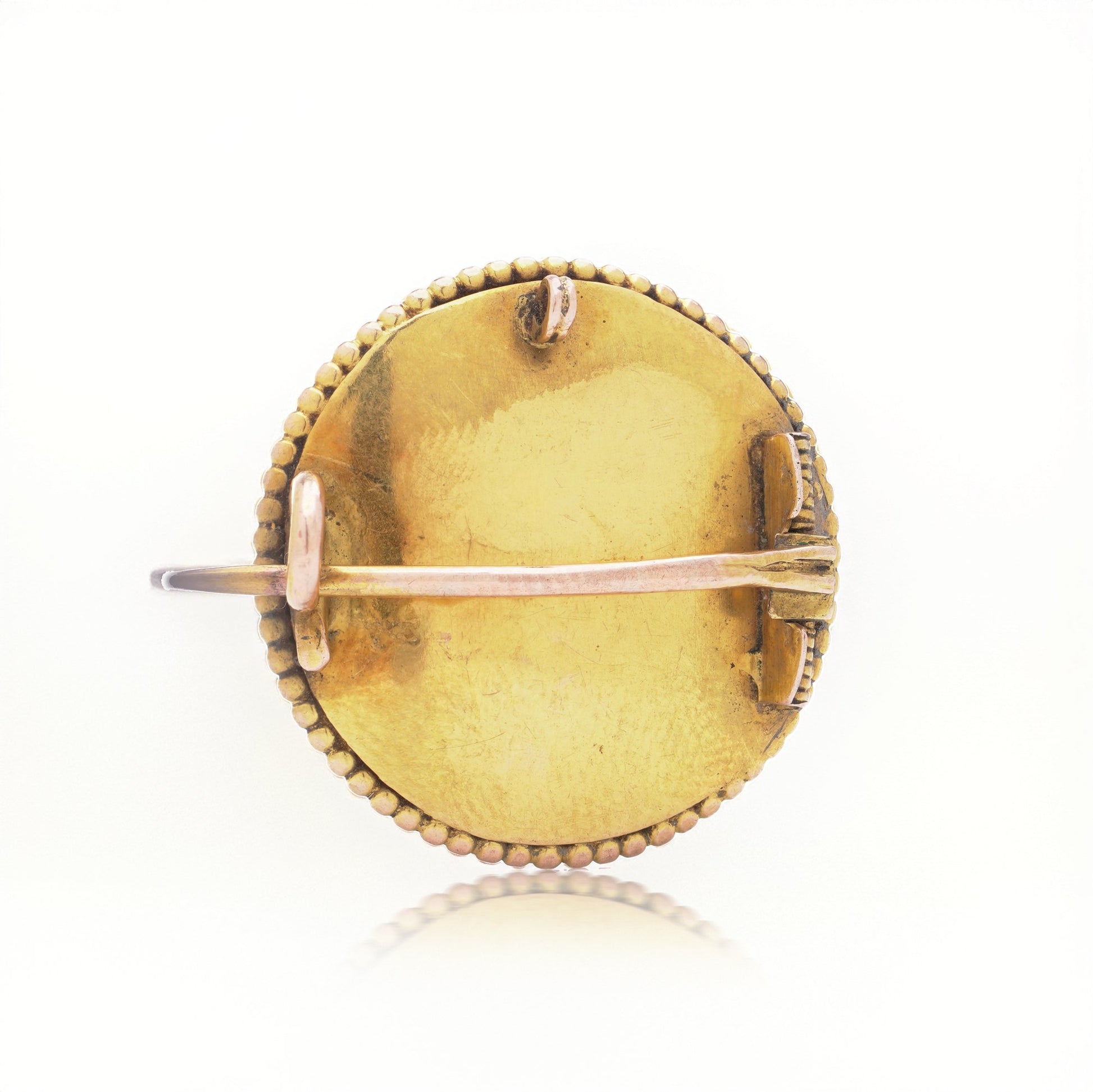 A yellow gold brooch back, on a white background
