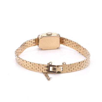 A yellow gold wristwatch with a brick link bracelet, on a white background