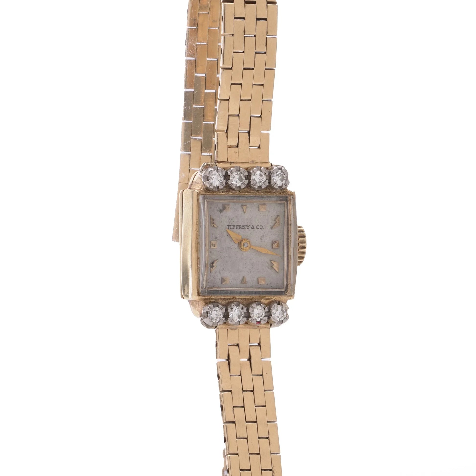 A yellow gold Tiffany & Co. diamond set wristwatch with a brick link bracelet, on a white background