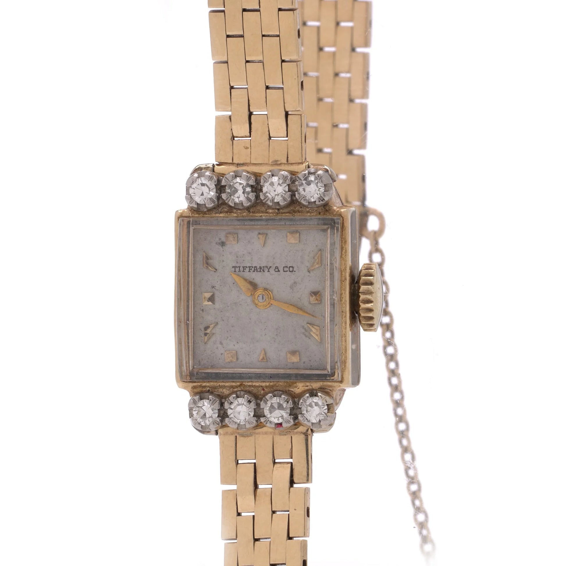 A yellow gold Tiffany & Co. diamond set wristwatch with a brick link bracelet, on a white background