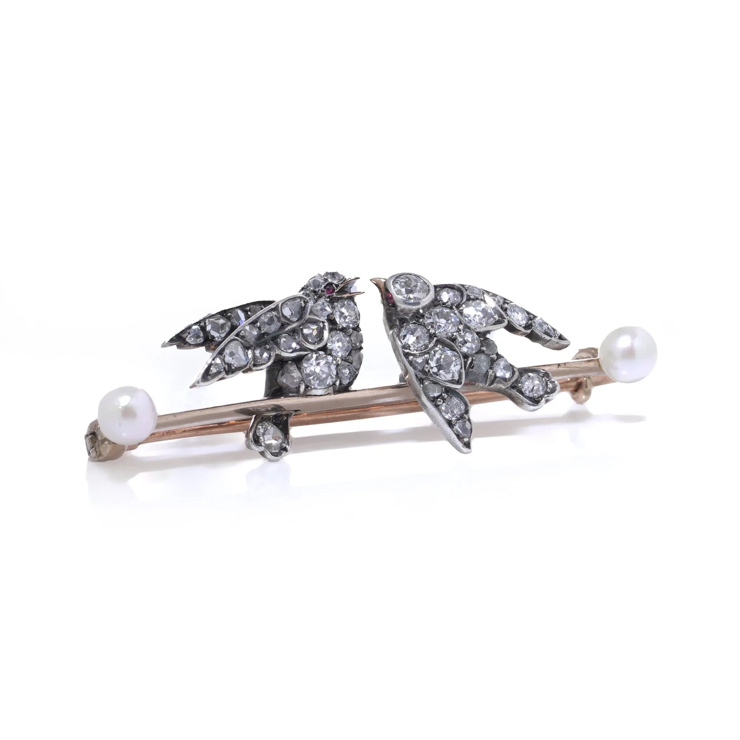 An antique bar brooch with two diamond set swallow birds, in gold and silver with pearls, on a white background