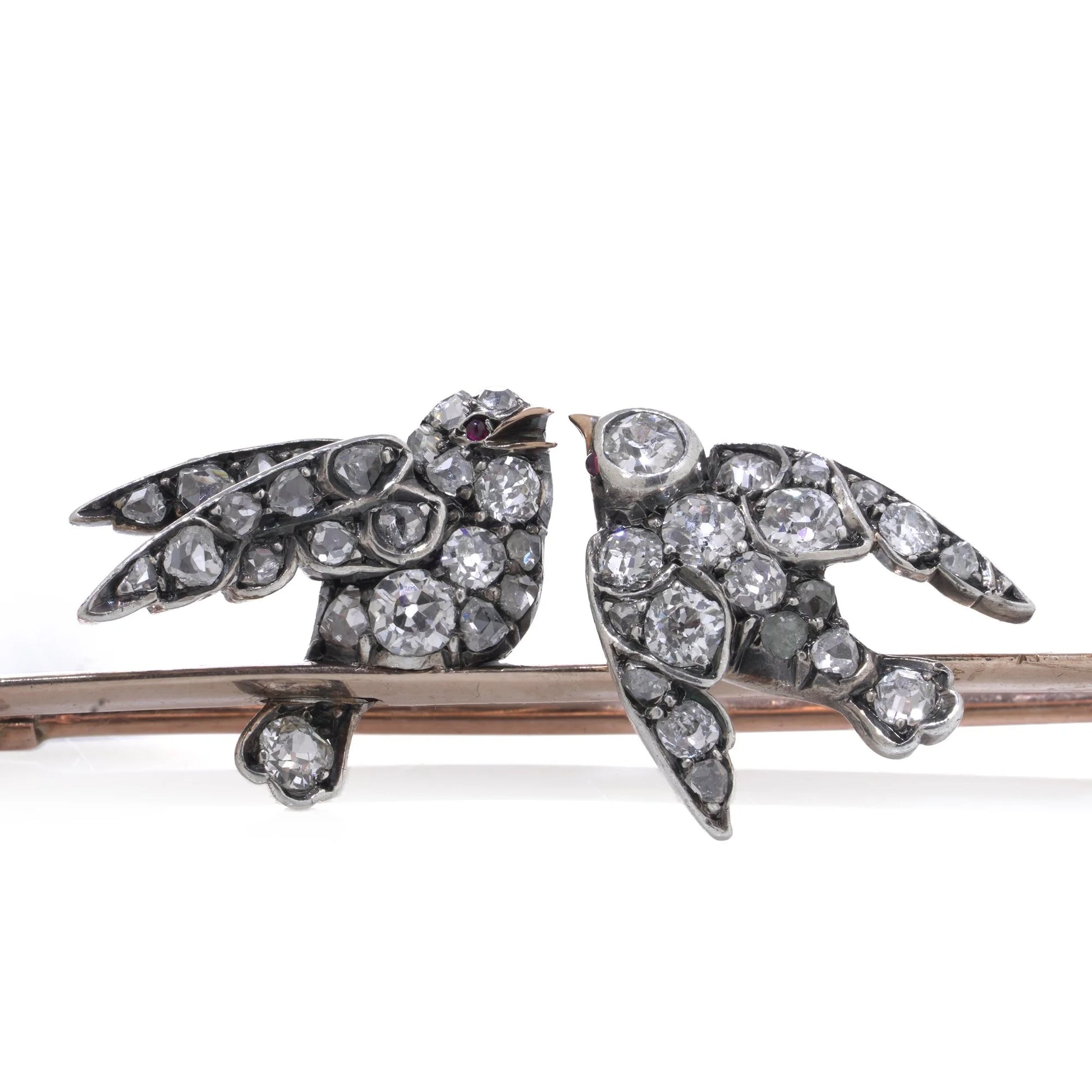 An antique bar brooch with two diamond set swallow birds, in gold and silver with pearls, on a white background