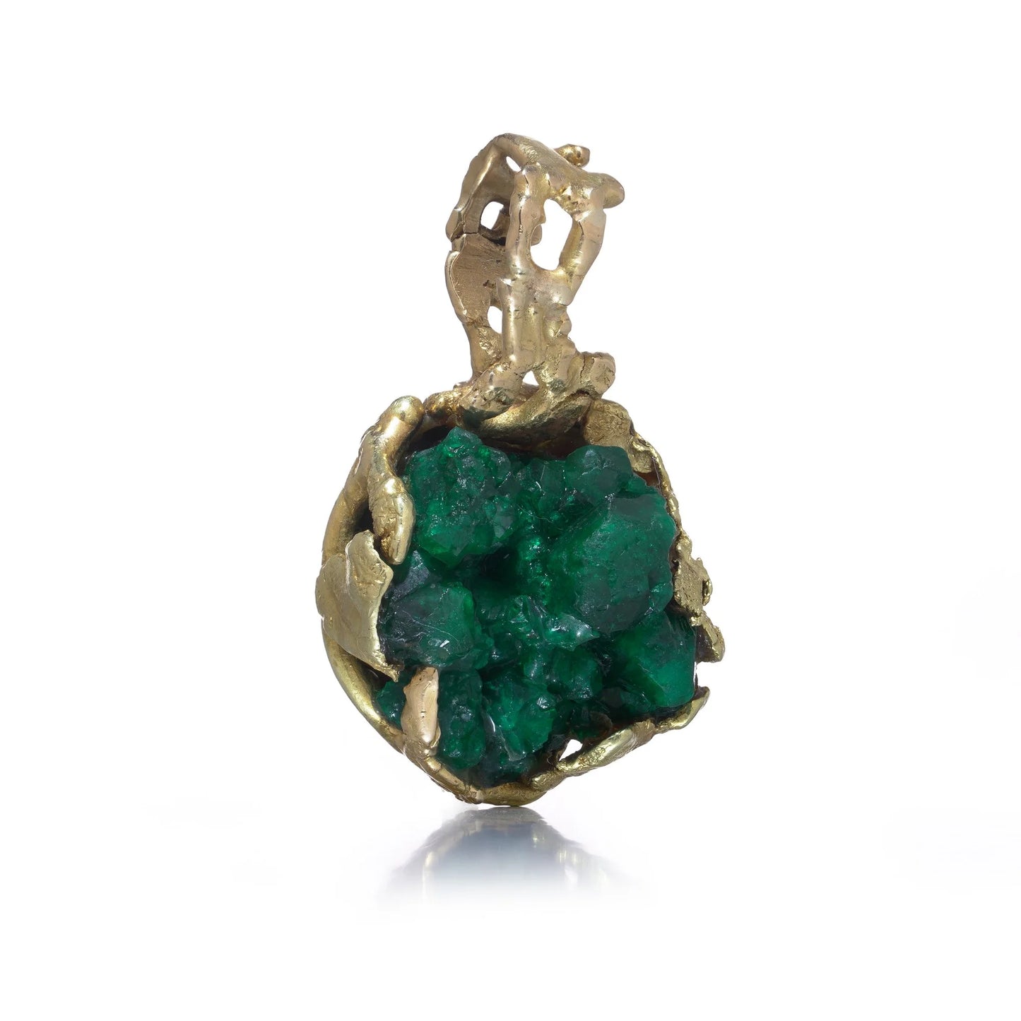 A yellow gold free-form pendant with a rough cut emerald, on a white background