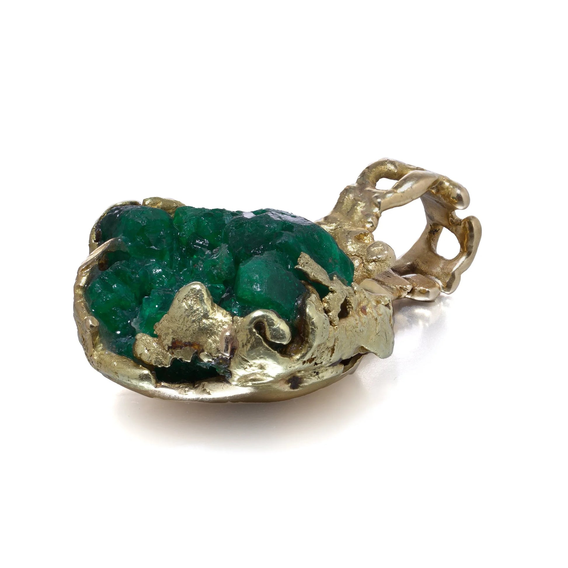 A yellow gold free-form pendant with a rough cut emerald, on a white background