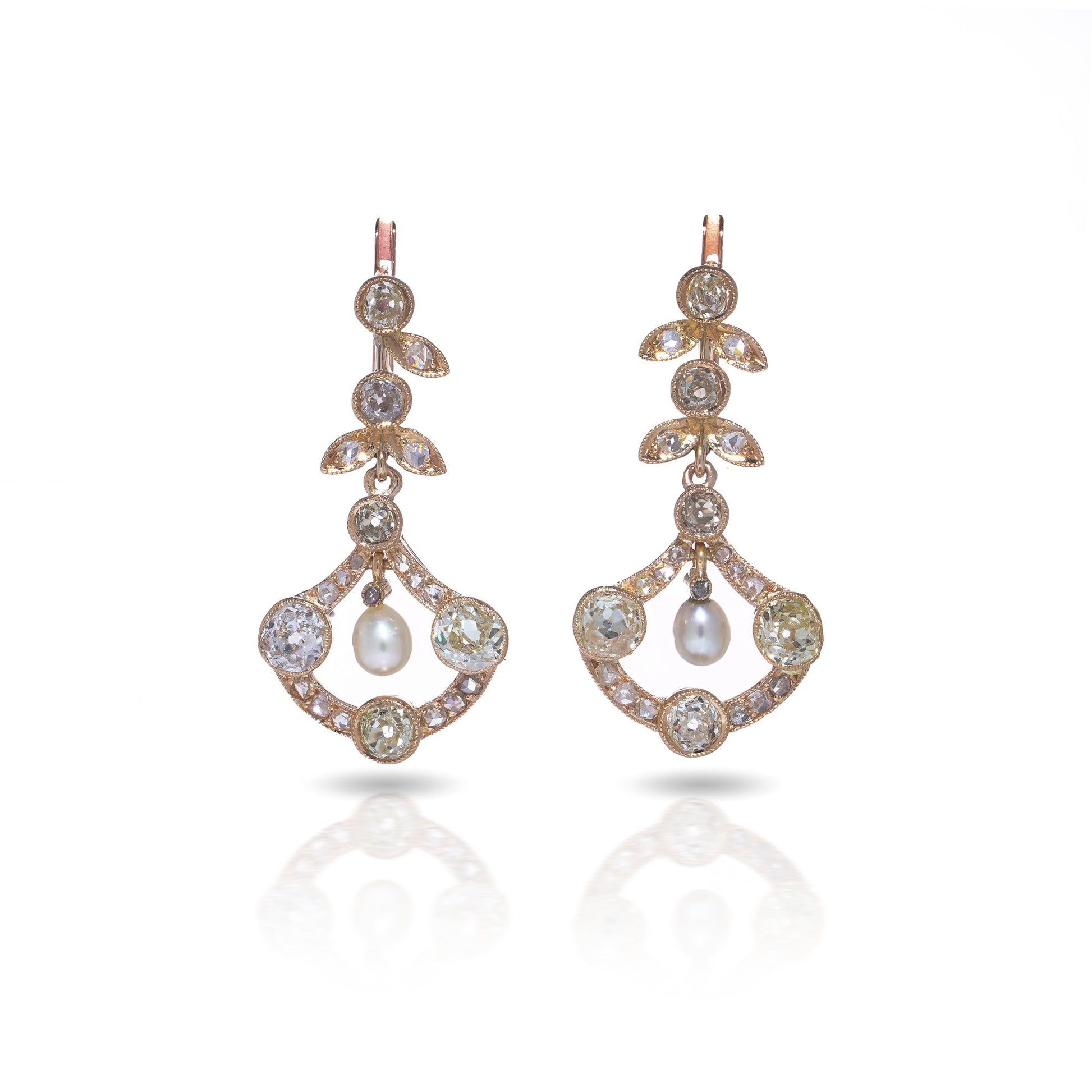 A pair of pearl and old cut diamond drop earrings with leaf motifs in yellow gold, on a white background