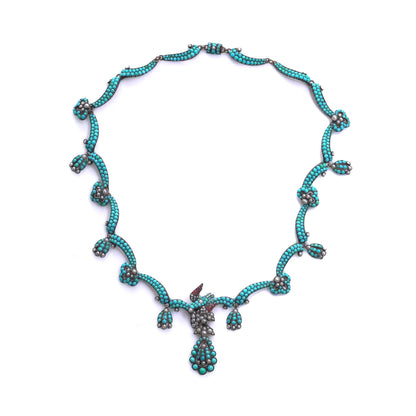 An antique turquoise bead and pearl fancy necklace with a bird motif, on a white background