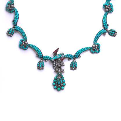 An antique turquoise bead and pearl fancy necklace with a bird motif, on a white background