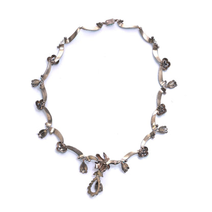 An antique silver fancy necklace with drop pendants, on a white background