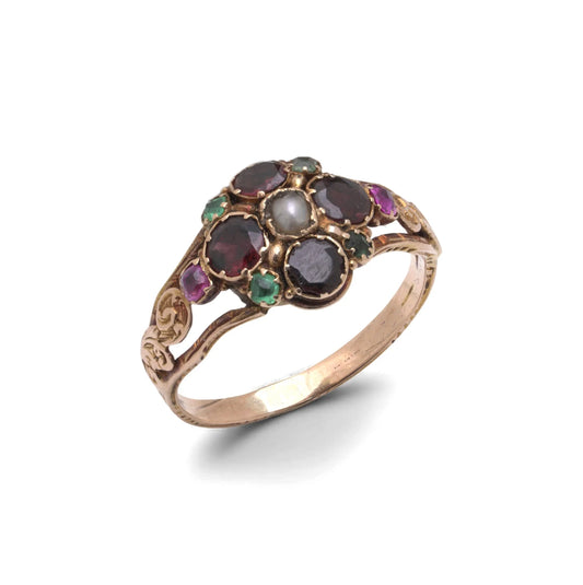 An antique gold ring with garnets, amethysts, green stones and a pearl, with decorative shoudlers, on a white background