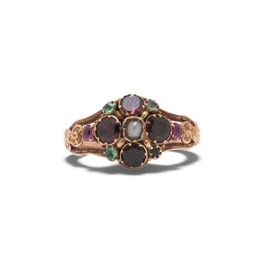 An antique gold ring with garnets, amethysts, green stones and a pearl, with decorative shoudlers, on a white background