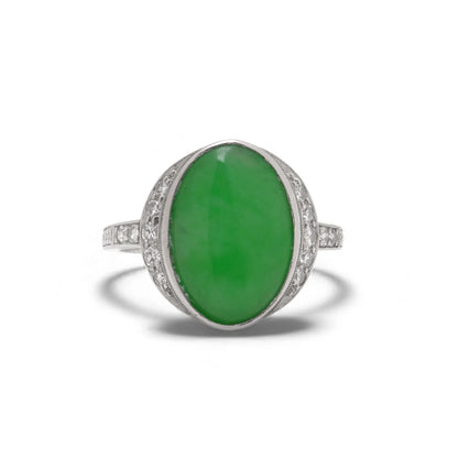 An Art Nouveau oval jade and diamond ring in platinum, against a white background