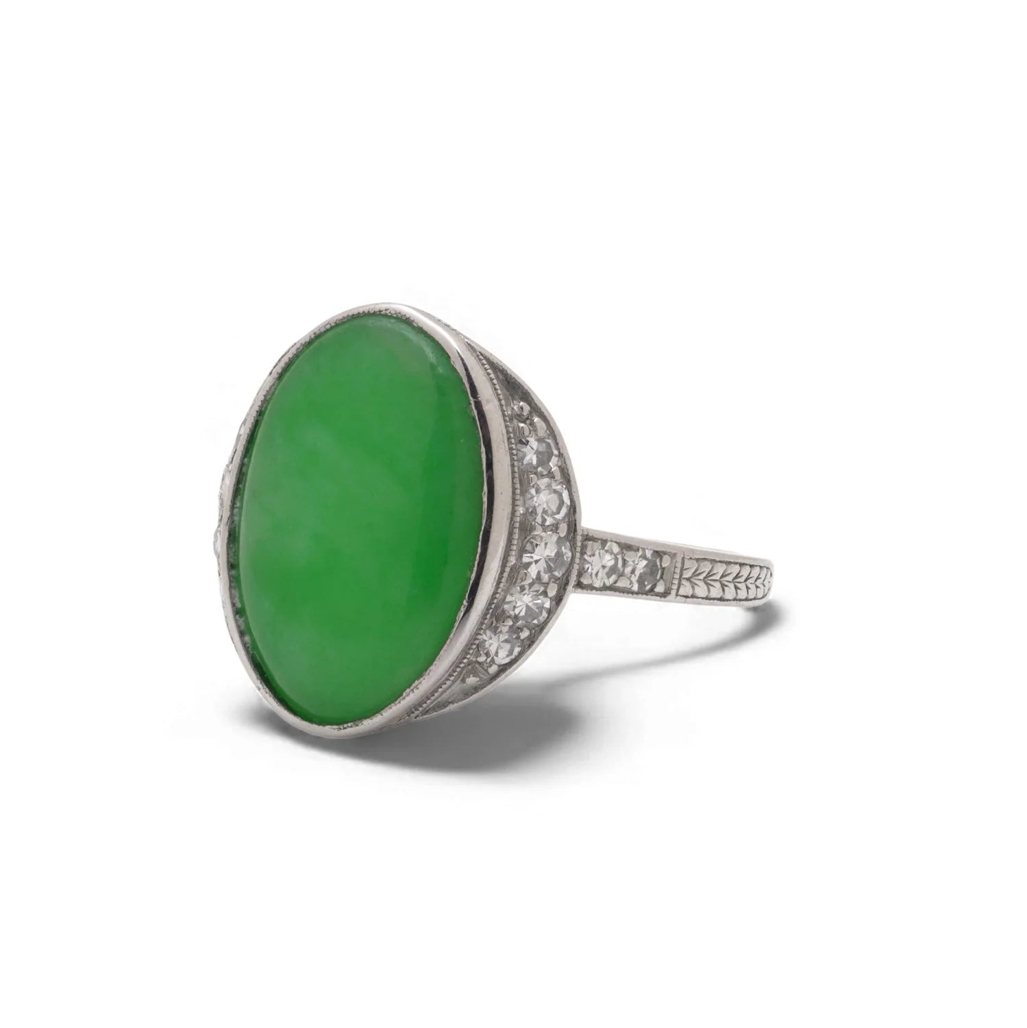 An Art Nouveau oval jade and diamond ring in platinum, against a white background