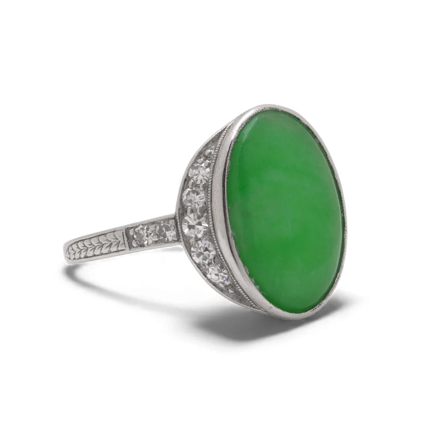 An Art Nouveau oval jade and diamond ring in platinum, against a white background
