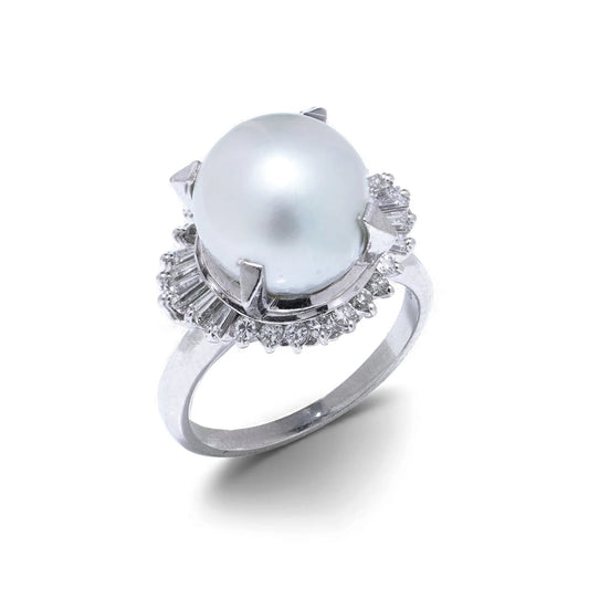 A platinum ring featuring a large white pearl surrounded by baguette and brilliant cut diamonds, on a white background