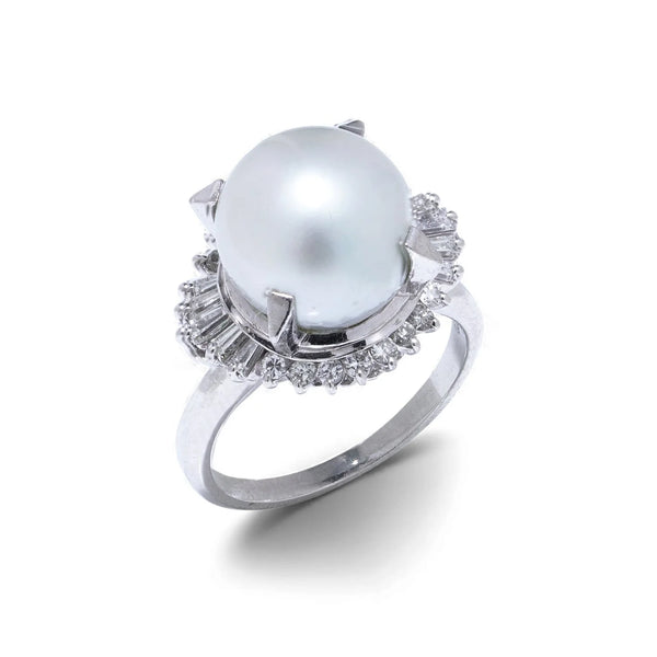 A platinum ring featuring a large white pearl surrounded by baguette and brilliant cut diamonds, on a white background