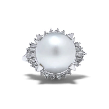 A platinum ring featuring a large white pearl surrounded by baguette and brilliant cut diamonds, on a white background