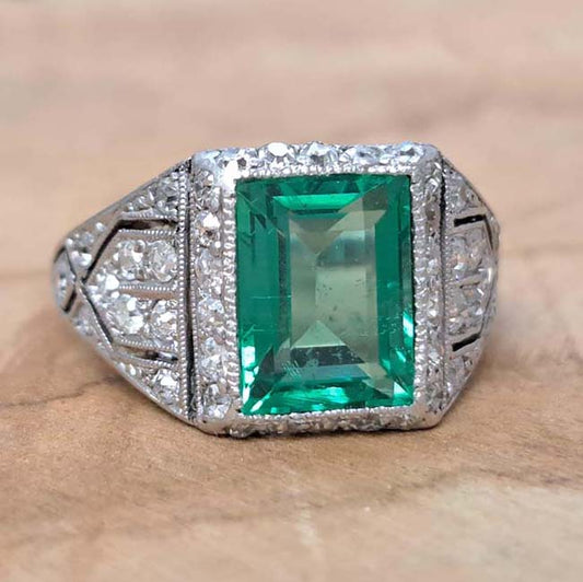 Belle Epoque Edwardian Antique 2.10ct Emerald and Diamond Cluster Ring in Platinum, 2.10ct rectangular step-cut vivid green emerald in diamond mount with openwork design to shoulders and scrolling gallery with engraved shank. Circa 1900