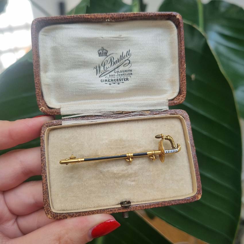 Vintage Gold and Enamel Sword Pin Brooch, yellow gold sword detailed with black enamel along the scabbard sheath and white enamel to the hilt with acorn/pineapple pendant drop