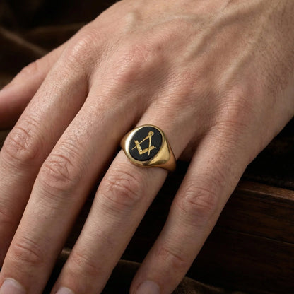 A yellow gold signet ring with an oval onyx masonic plaque, modelled on a hand