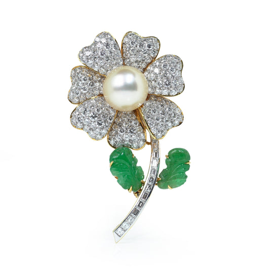 A flower brooch set with diamonds, a pearl centre and emerald leaves, in yellow and white gold