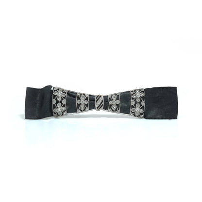 A floral design diamond and platinum bow brooch with a black ribbon